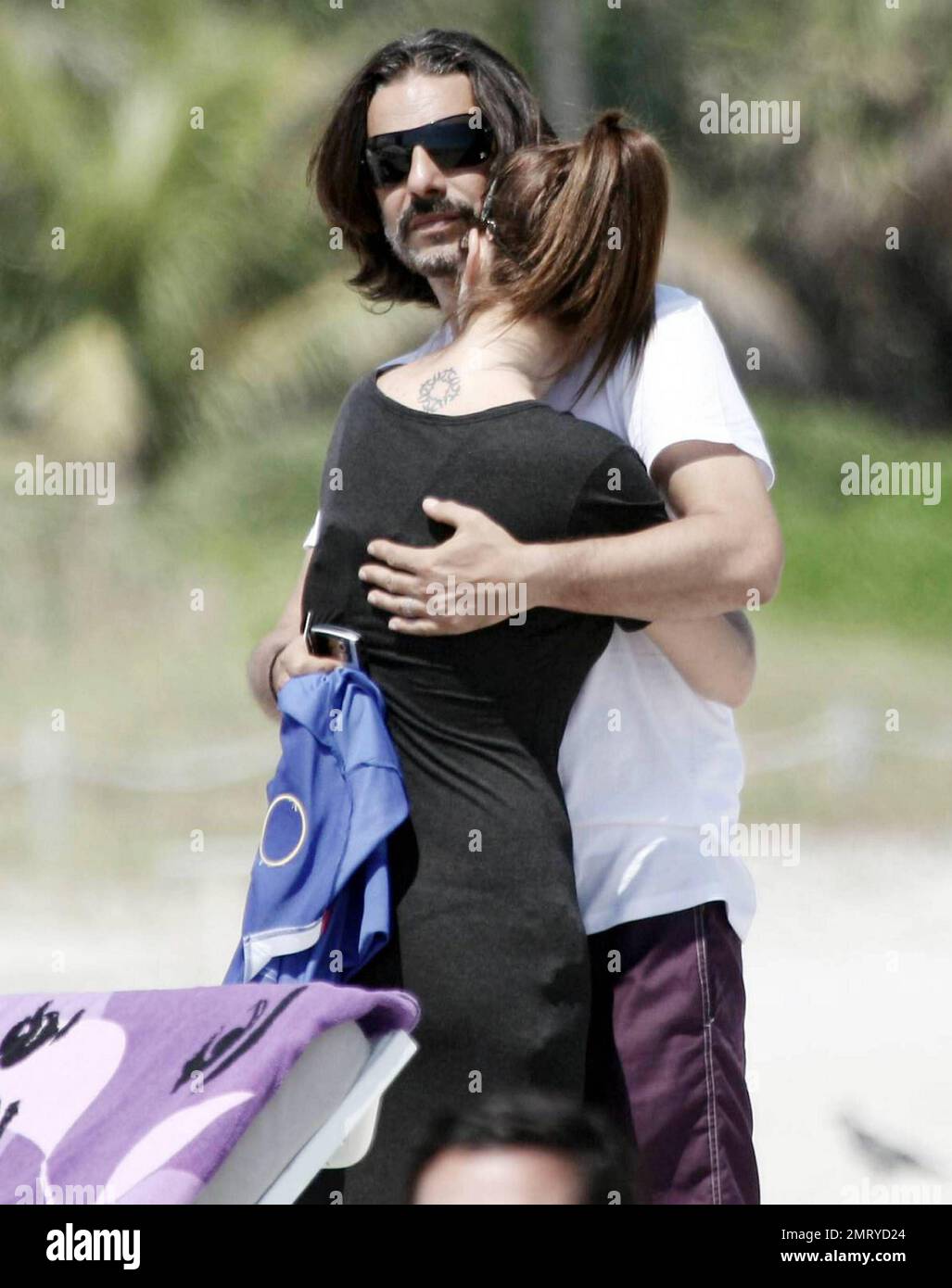 Argentinian actor Fabian Mazzei hugs his girlfriend, Argentinian model and actress Araceli Gonzalez, while they spend some quality time together with family on the beach in Miami.  Gonzalez, who smiled for photographers as she walked away from the beach in her long black cover up, appeared very happy as she carried her Louis Vuitton tote bag and Nylon magazine.  Miami, FL. 10/02/10. Stock Photo