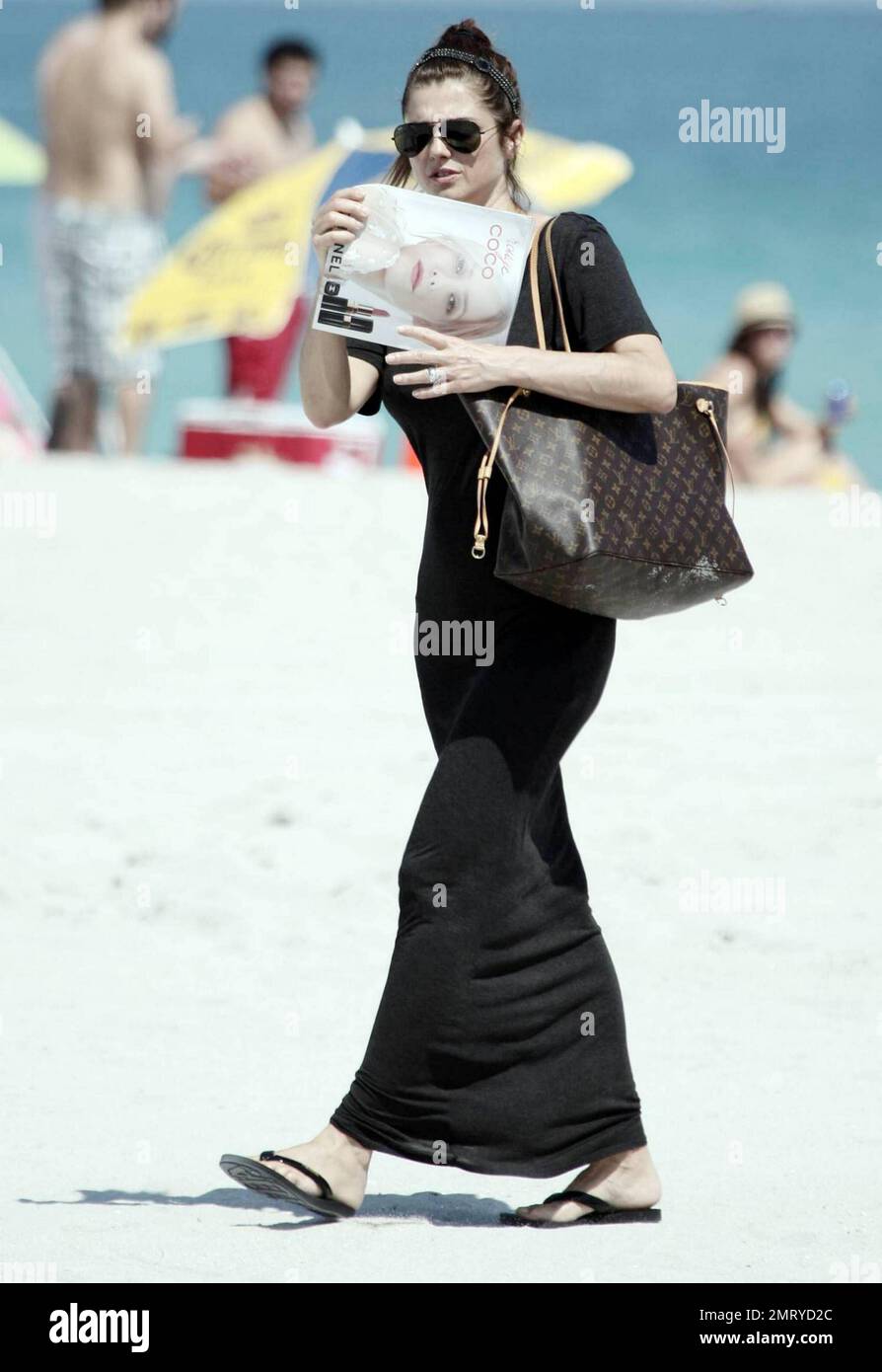 Argentinian actor Fabian Mazzei hugs his girlfriend, Argentinian model and actress Araceli Gonzalez, while they spend some quality time together with family on the beach in Miami.  Gonzalez, who smiled for photographers as she walked away from the beach in her long black cover up, appeared very happy as she carried her Louis Vuitton tote bag and Nylon magazine.  Miami, FL. 10/02/10. Stock Photo