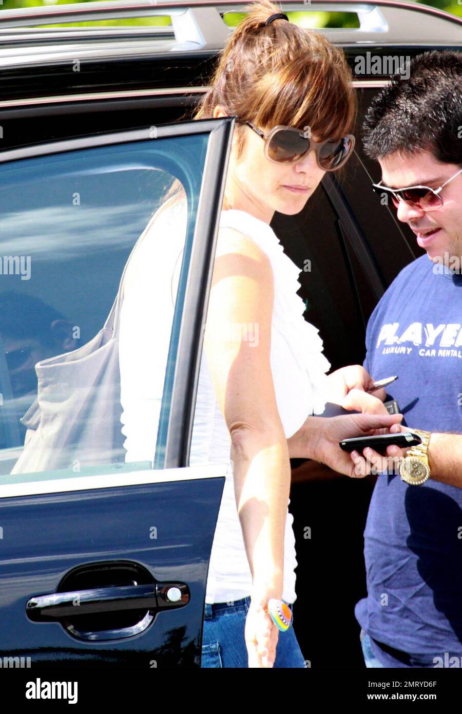 Argentinian couple, actor Fabian Mazzei and girlfriend model and actress Araceli Gonzalez appear to pay a valet at their luxury hotel before heading off after a weekend getaway in Miami.  Friendly Araceli, decked out in a simple white one-shoulder ruffle top, flare jeans and cute wedge platforms, dealt with the staff while Fabian and son waited in the car.  Miami, FL. 10/03/10. Stock Photo