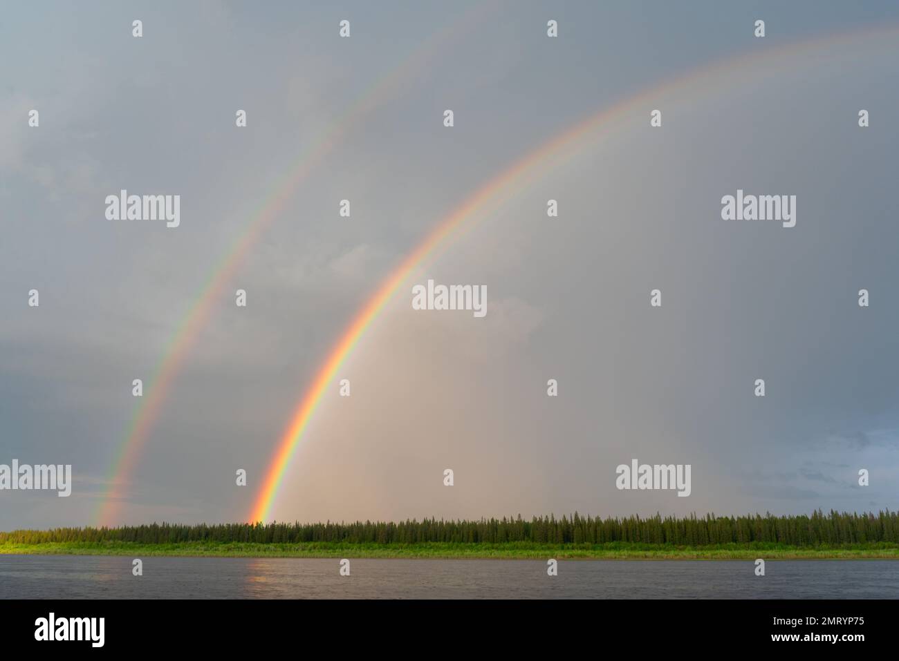 Bright double rainbow in clouds and blue sky during rain on the Vilyui ...