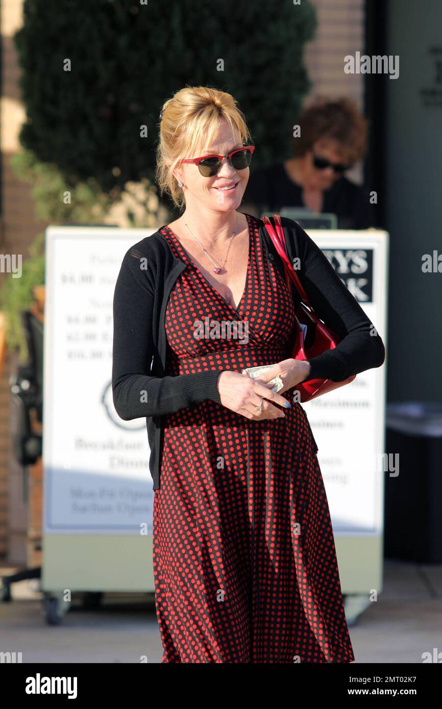 Melanie Griffith wears a brown dress with red polka dots and black sweater  paired with red high heels and a matching purse as she gets in some  shopping at Barney's New York.