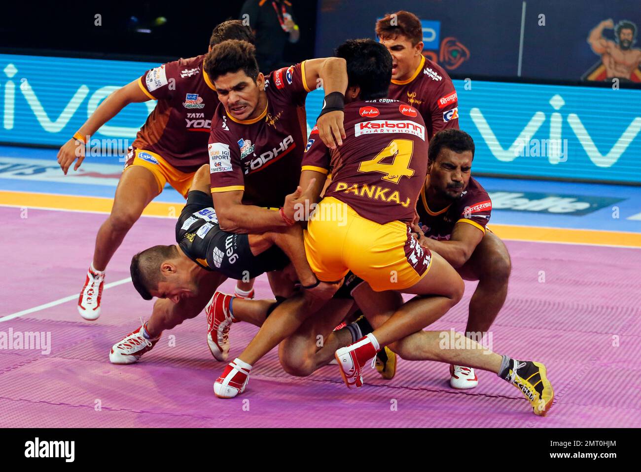 U.P. Yoddha's players pin down Telugu Titan's player, in black