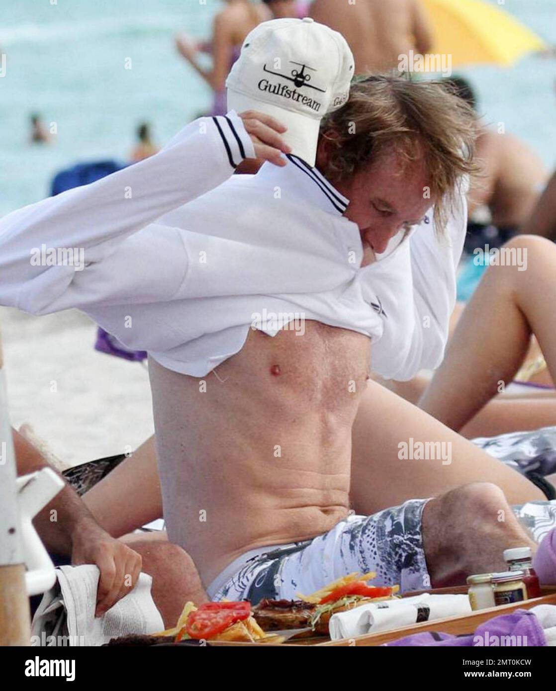 Blockbuster-making director Michael Bay hangs out at the beach with some friends over the Labor Day long weekend.  Bay, who is currently filming 'Transformers 3', showed off his trim physique as he put his shirt on before enjoying a newspaper followed by a burger and french fry lunch.  Bay has recently been in the news as he reportedly pledged a $50,000 reward to anyone who will identify a mystery woman who was video taped throwing live puppies in to a river, a video that can be seen on such websites as YouTube. Miami, FL. 09/04/10. Stock Photo