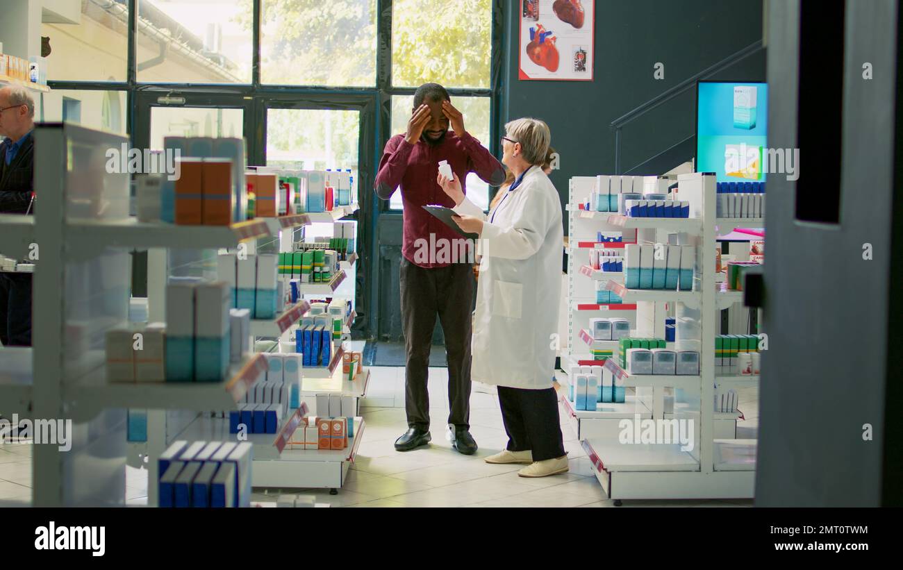 Sick male client entering drugstore with painful headache, asking ...