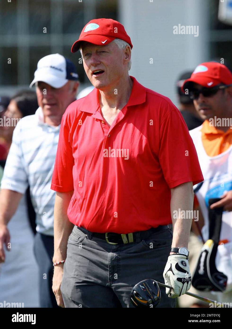 Exclusive!! President Bill Clinton plays on day three of The Michael Jordan Celebrity Invitational golf tournament held at the luxurious One and Only Ocean Club Golf Course on Paradise Island. At one point, Young hit one into the rough which, in this case, was the beach on the other side of a wall! He worked very hard to get it back onto the course. At least it didn't end up in the ocean. The MJCI organization brings in an incredible array of talent from the worlds of sport and entertainment to compete on the course and participate in various events for charity in this annual event.  In it's s Stock Photo