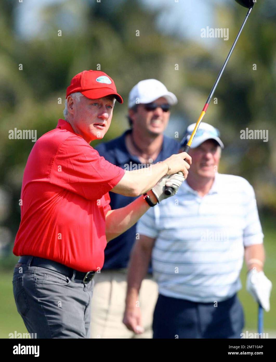 Exclusive!! President Bill Clinton plays on day three of The Michael Jordan Celebrity Invitational golf tournament held at the luxurious One and Only Ocean Club Golf Course on Paradise Island. At one point, Young hit one into the rough which, in this case, was the beach on the other side of a wall! He worked very hard to get it back onto the course. At least it didn't end up in the ocean. The MJCI organization brings in an incredible array of talent from the worlds of sport and entertainment to compete on the course and participate in various events for charity in this annual event.  In it's s Stock Photo