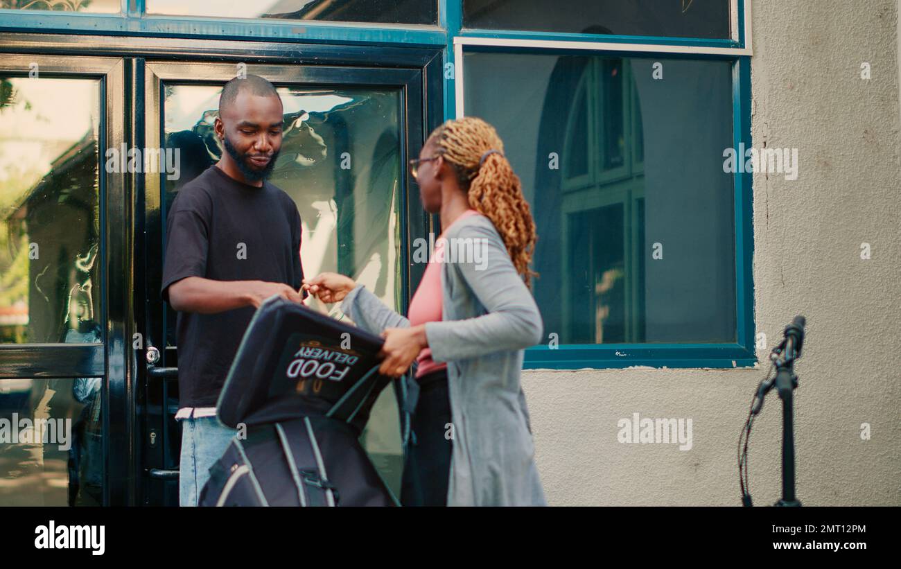 Fastfood employee giving meal package order to client, man paying for ...