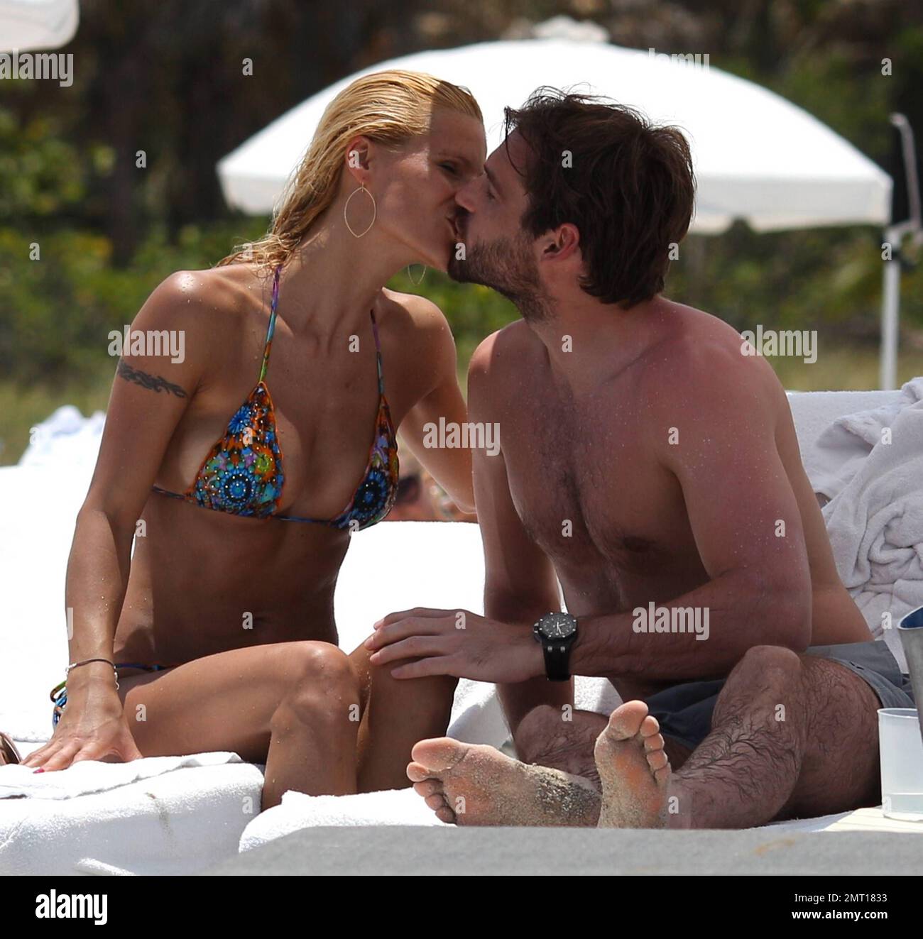 Swiss TV host and actress Michelle Hunziker spends the day in Miami Beach with boyfriend Tomaso Trussardi. 35 year old Hunziker wore a multi-color string bikini that showed off her amazing toned figure. The couple were seen taking a dip in the ocean and happily walking hand-in-hand. Miami Beach, FL. 3rd June 2012. . Stock Photo