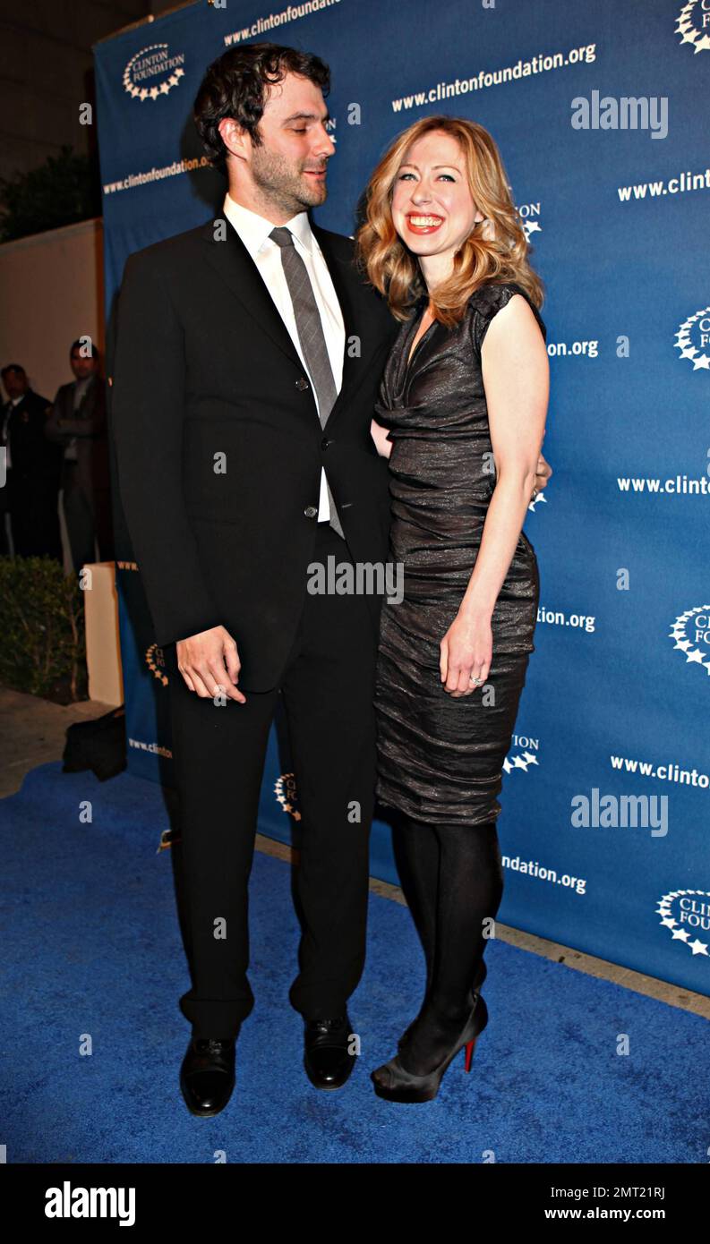 In a slimming black cocktail dress Chelsea Clinton beams as she holds hands  with husband Marc Mezvinsky on the blue carpet during Millennium Network  Event hosted by former US President Bill Clinton