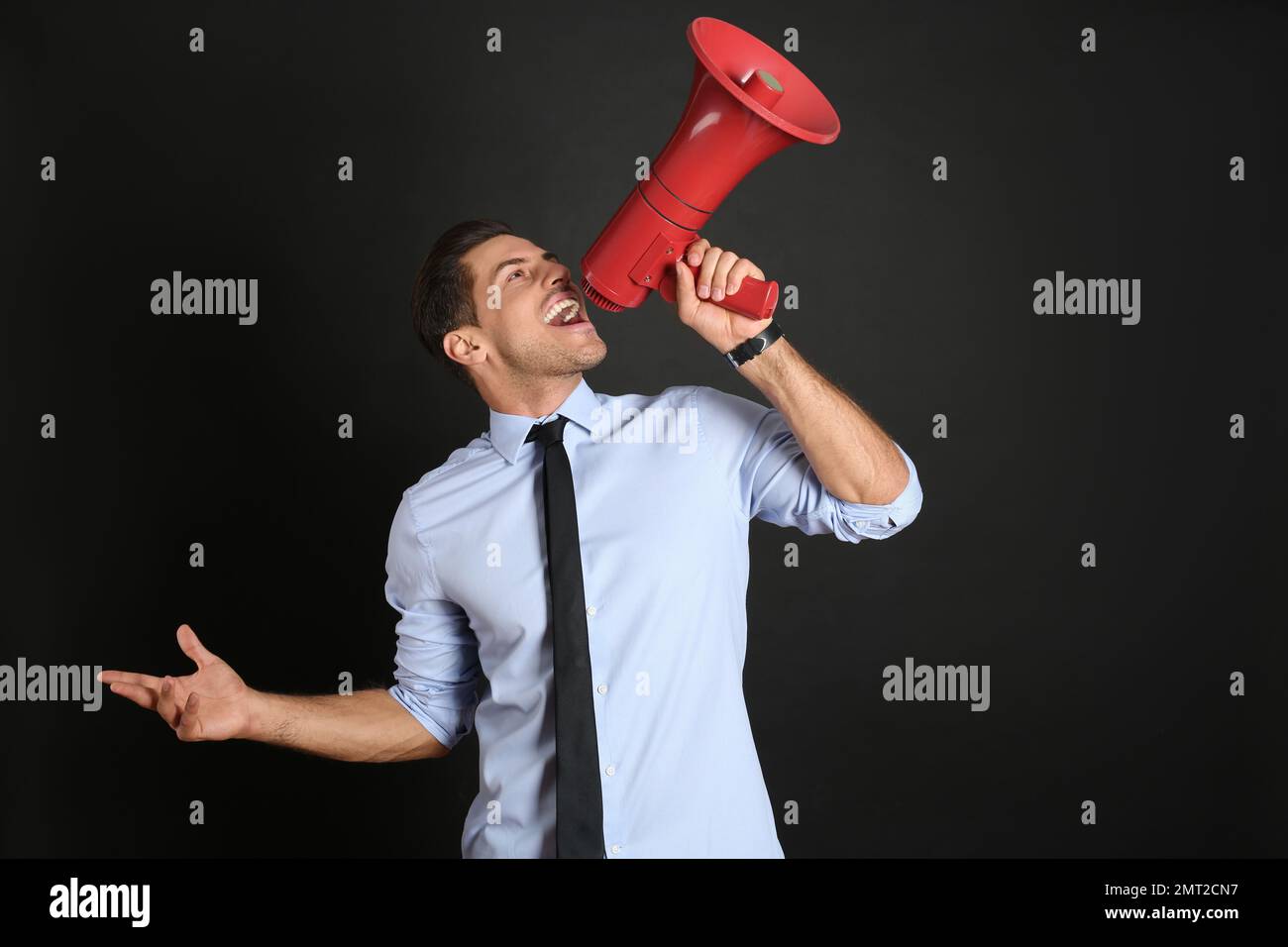 Handsome man with megaphone on black background Stock Photo