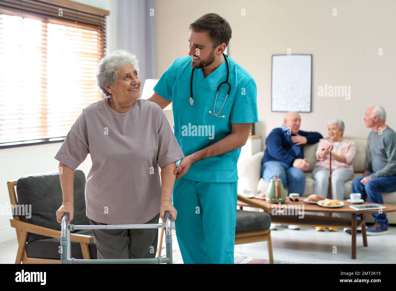 Care worker helping to elderly woman with walker in geriatric hospice Stock Photo