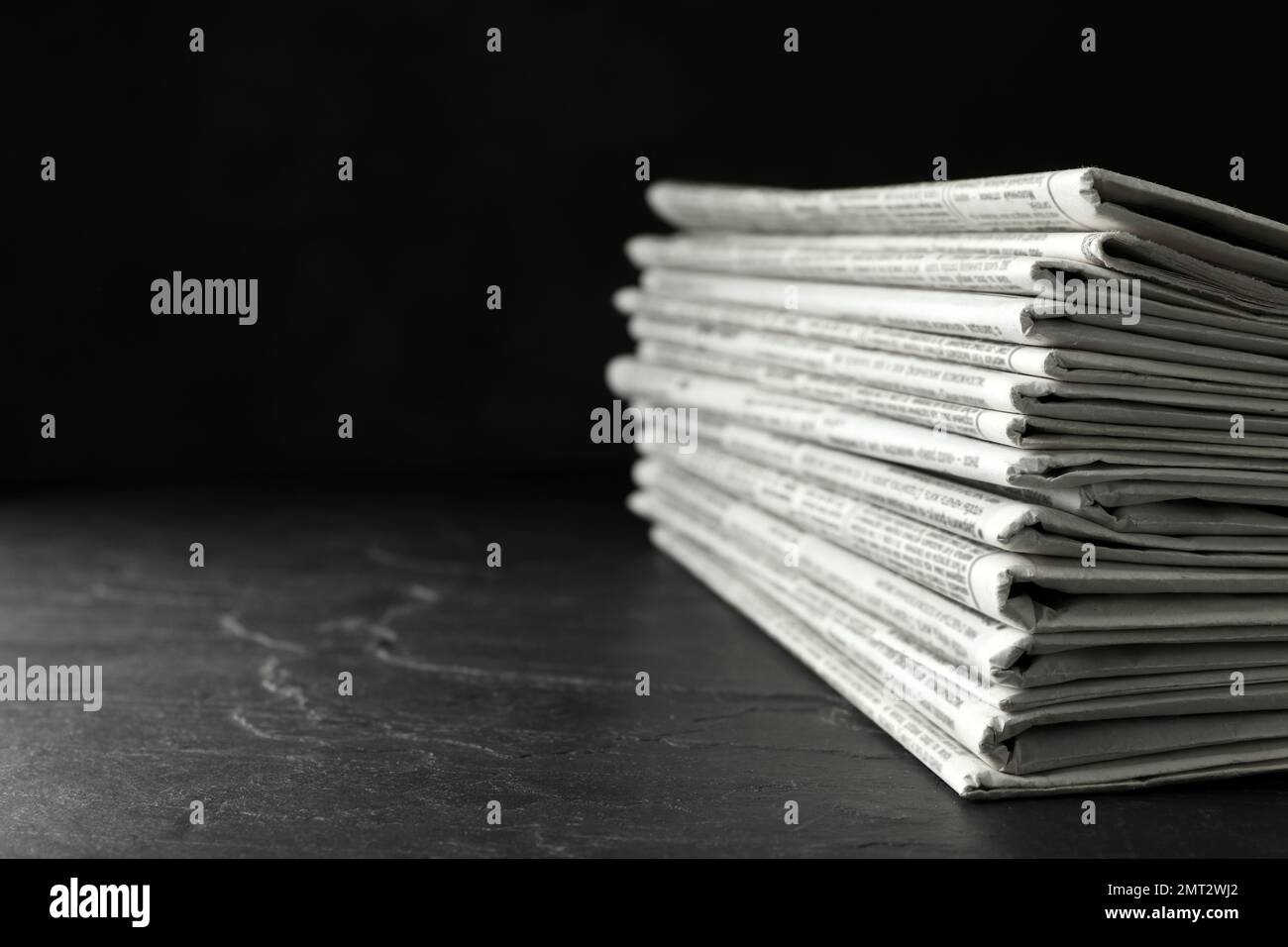 Stack of newspapers on dark stone table, space for text. Journalist's work Stock Photo