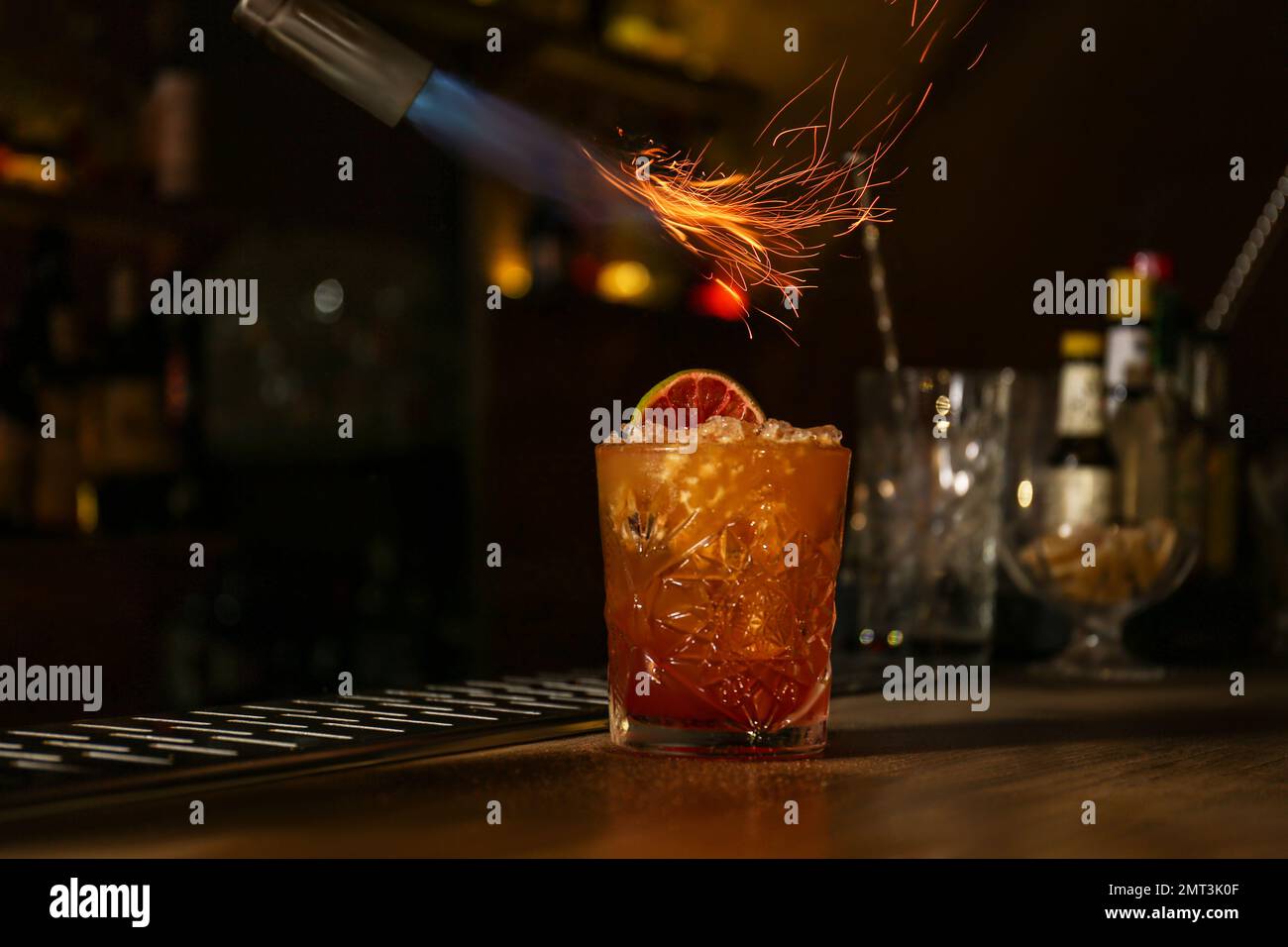 Preparing fresh alcoholic cocktail with flame at bar counter Stock Photo