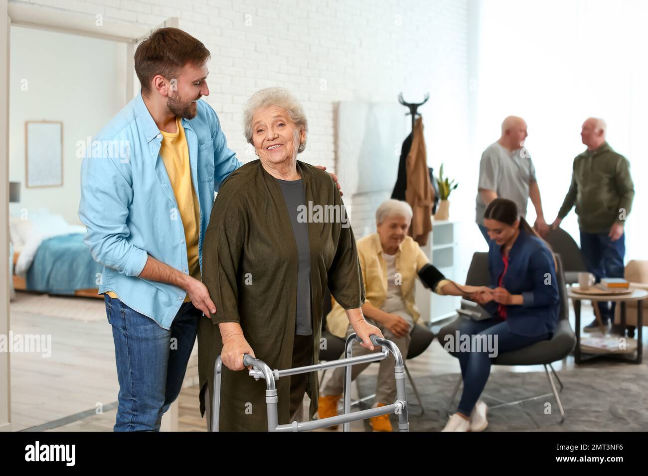 Care worker helping to elderly woman with walker in geriatric hospice Stock Photo