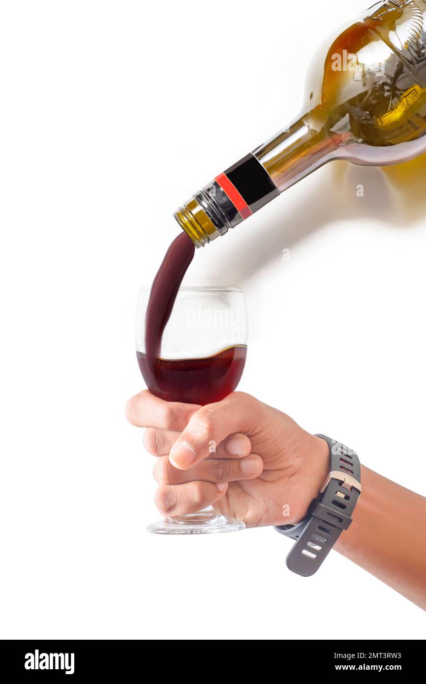 A vertical shot of pouring the red wine into the glass in the hand of a