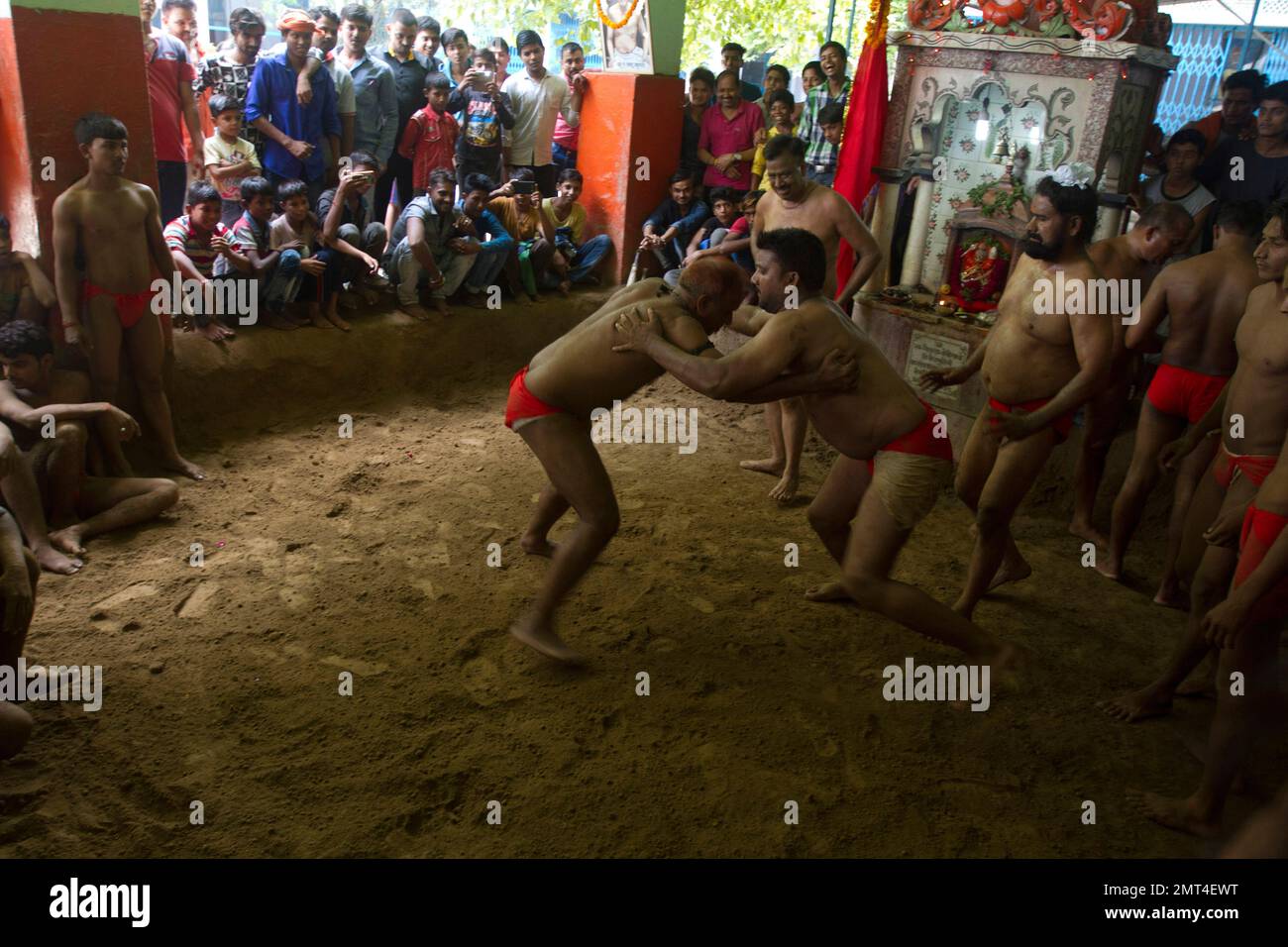 People watch Indian traditional wrestlers engage in a bout of wrestling during Nag Panchami