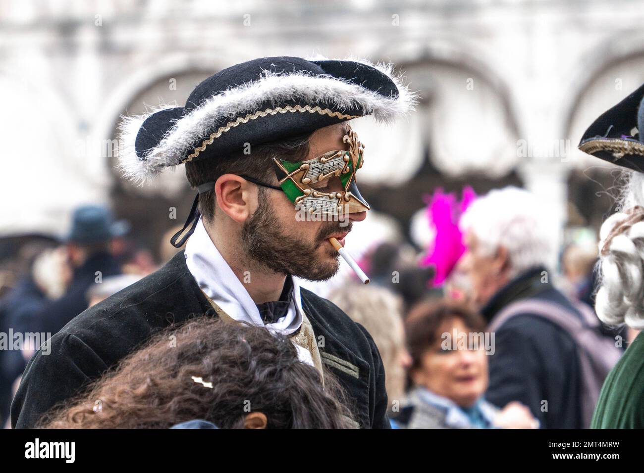 Handsome young man in carnival mask wearing tricorn with an unlit ...