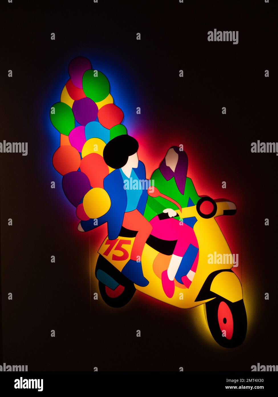 A  colourful vintage display sign made of glowing plastic of a couple on a vespa. at the museum Vespa scooters at the Piaggio museum, Pontedera, Italy Stock Photo