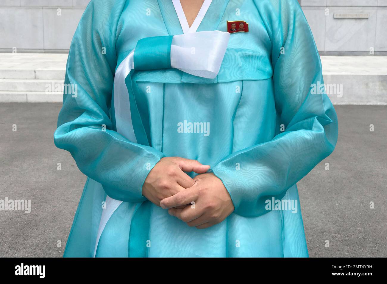In this Wednesday, July 26, 2017, photo, a factory guide in a traditional Korean dress with the faces of the late North Korean leaders Kim Il Sung and Kim Jong Il pinned above her heart on the left of her dress, speaks to visiting media in Pyongyang, North Korea. (AP Photo/Wong Maye-E) Stock Photo