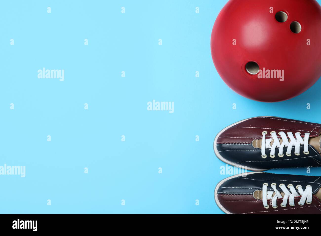 Bowling ball and shoes on light blue background, flat lay. Space for