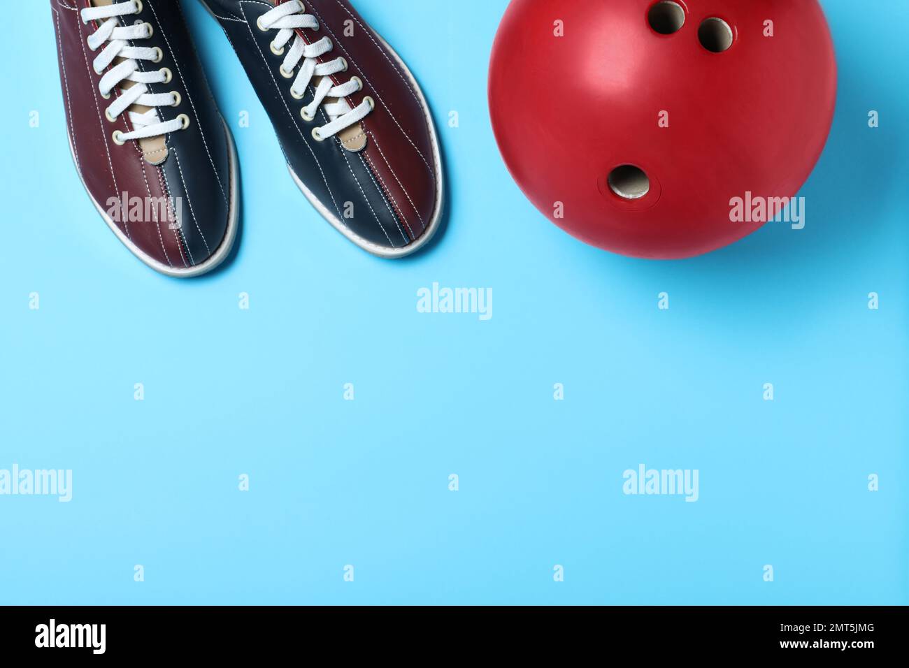 Bowling ball and shoes on light blue background, flat lay. Space for