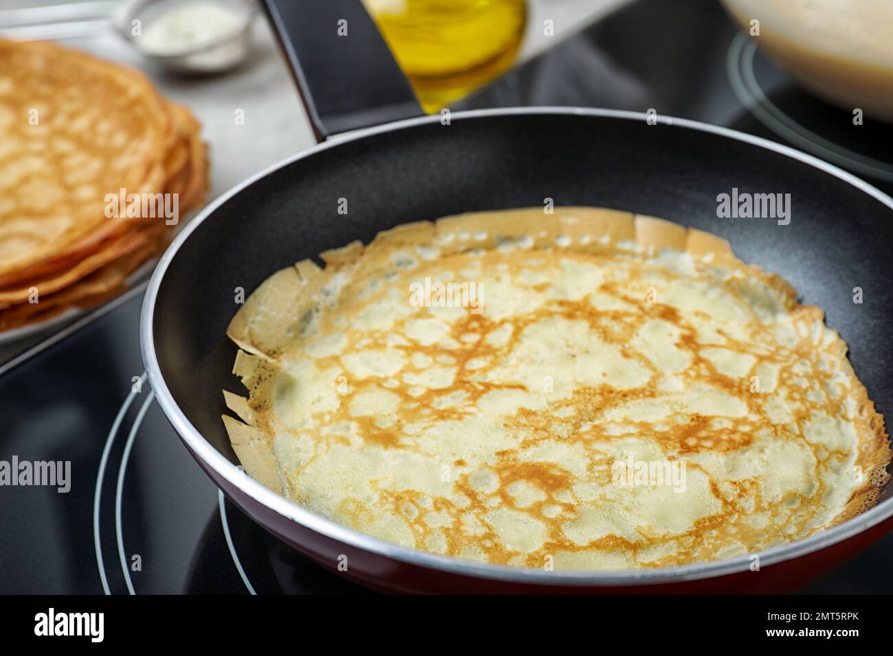 Delicious thin pancake in frying pan on induction stove, closeup Stock