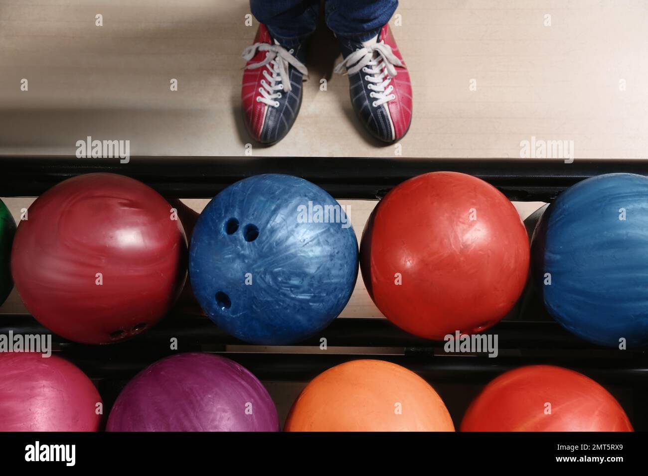 Person in bowling shoes near rack with balls, top view Stock Photo Alamy
