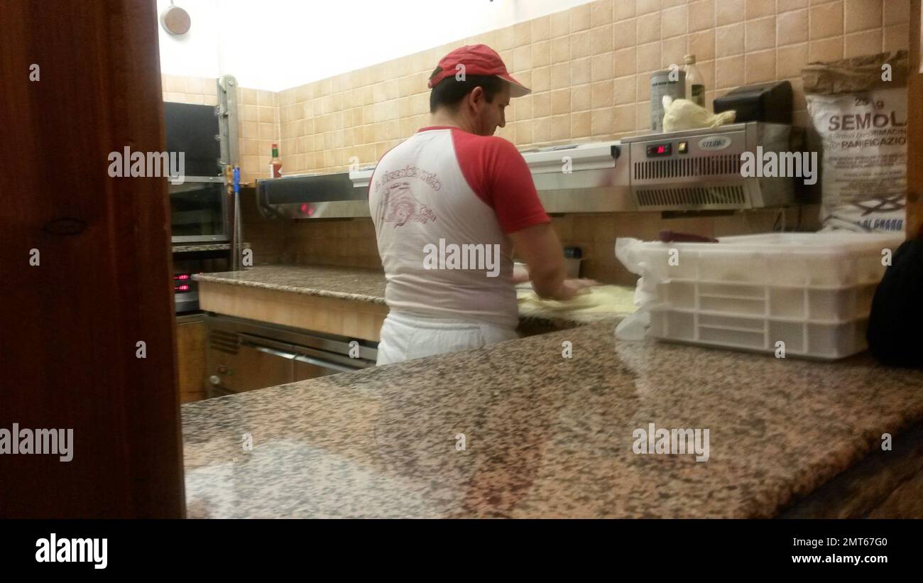 Pizza maker in a pizzeria in front of the oven Stock Photo