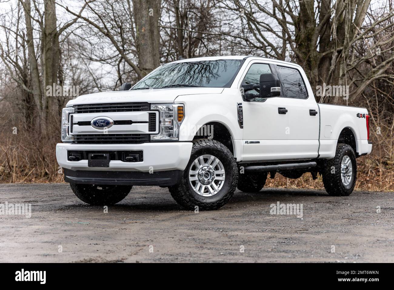 A white 2020 Ford F-250 pickup truck with lifted wheels on a dirt road