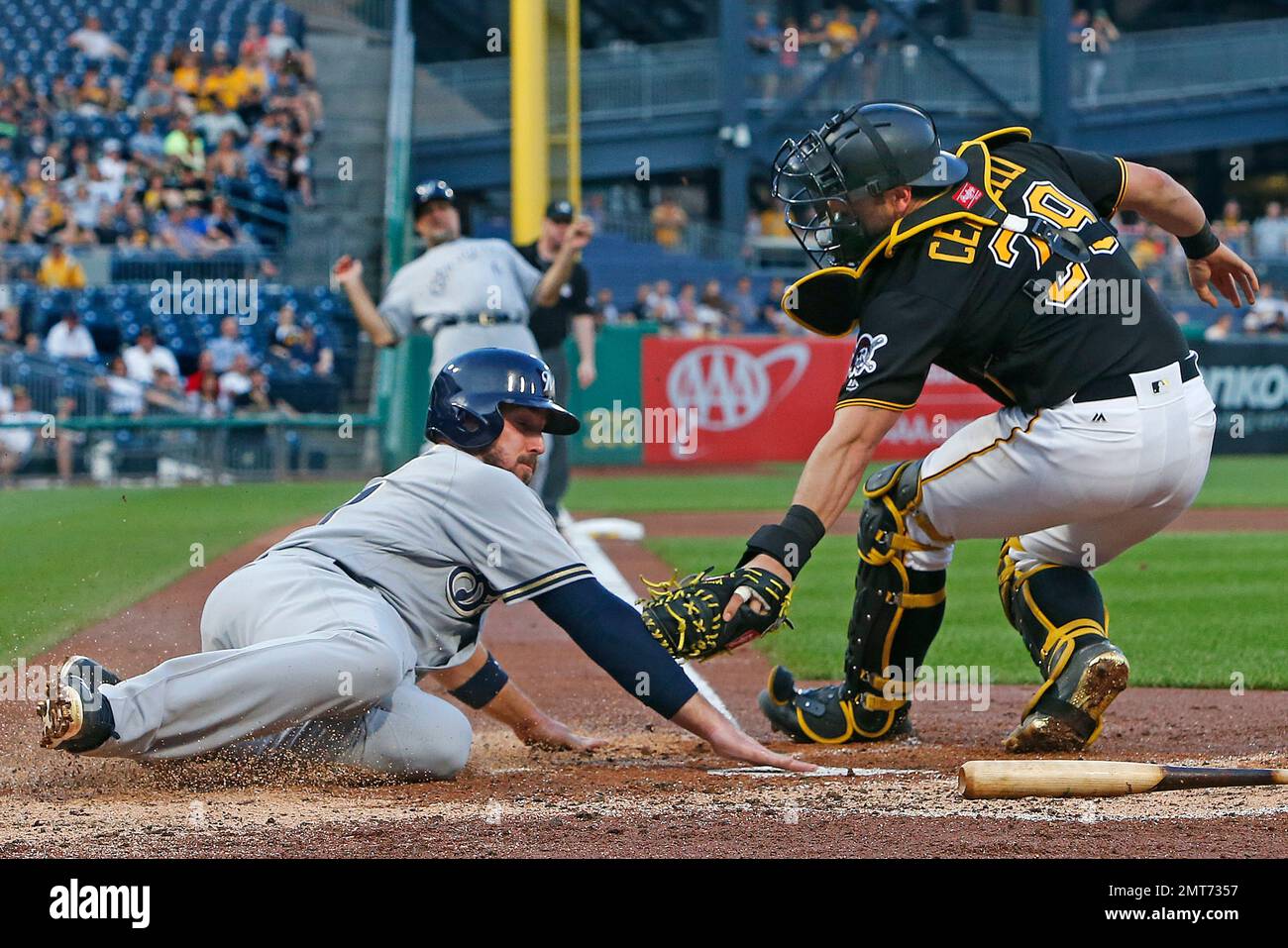 Milwaukee Brewers' Travis Shaw, center, slides safely under the swipe tag  by Pittsburgh Pirates catcher Francisco Cervelli, right, with umpire Mike  Winters watching the play, in the fourth inning of a baseball