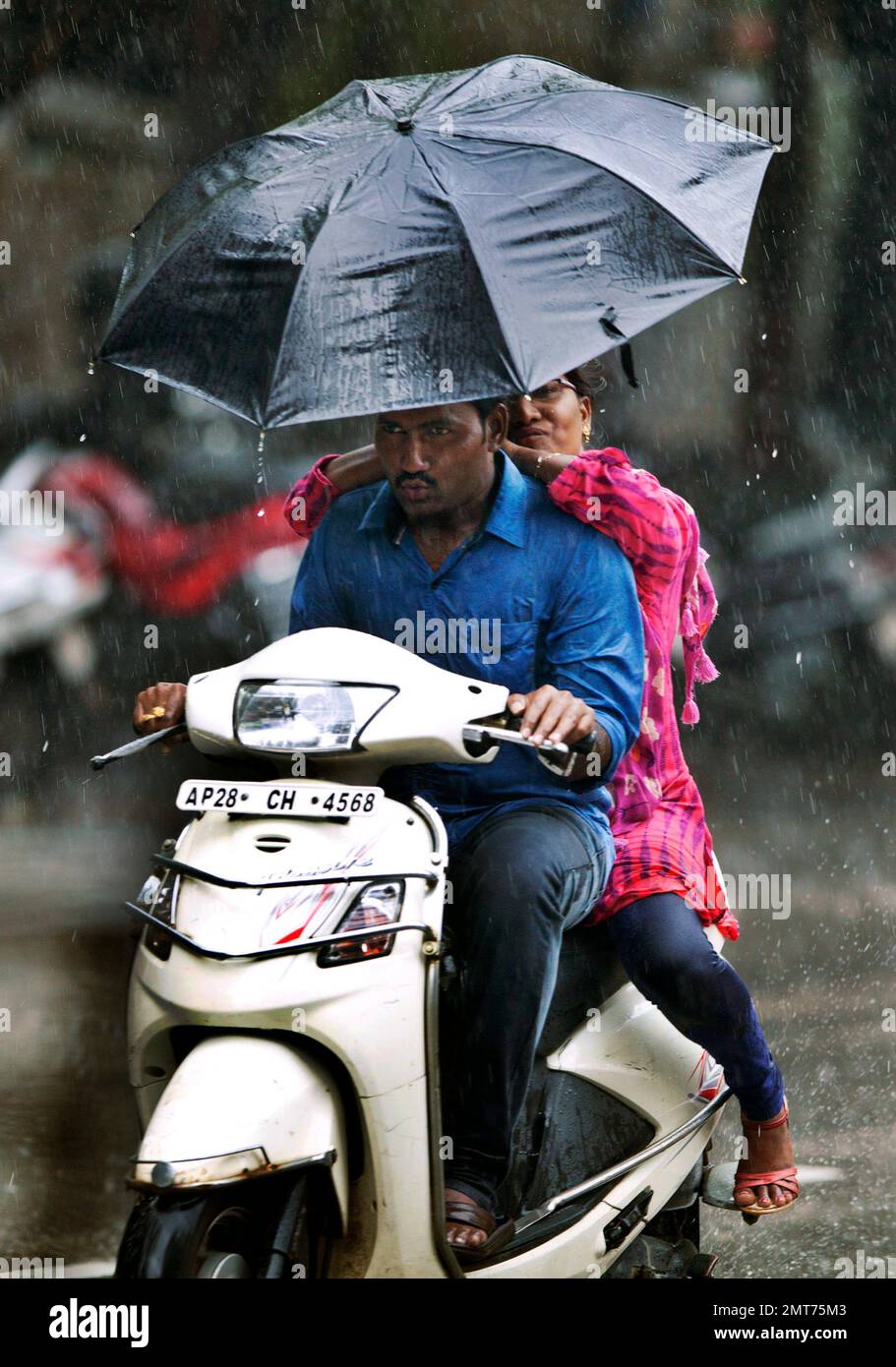 An Indian woman holds an umbrella as she pillion rides a scooter during monsoon rains in Hyderabad India Monday July 17 2017. India receives its monsoon rains from June to September. AP