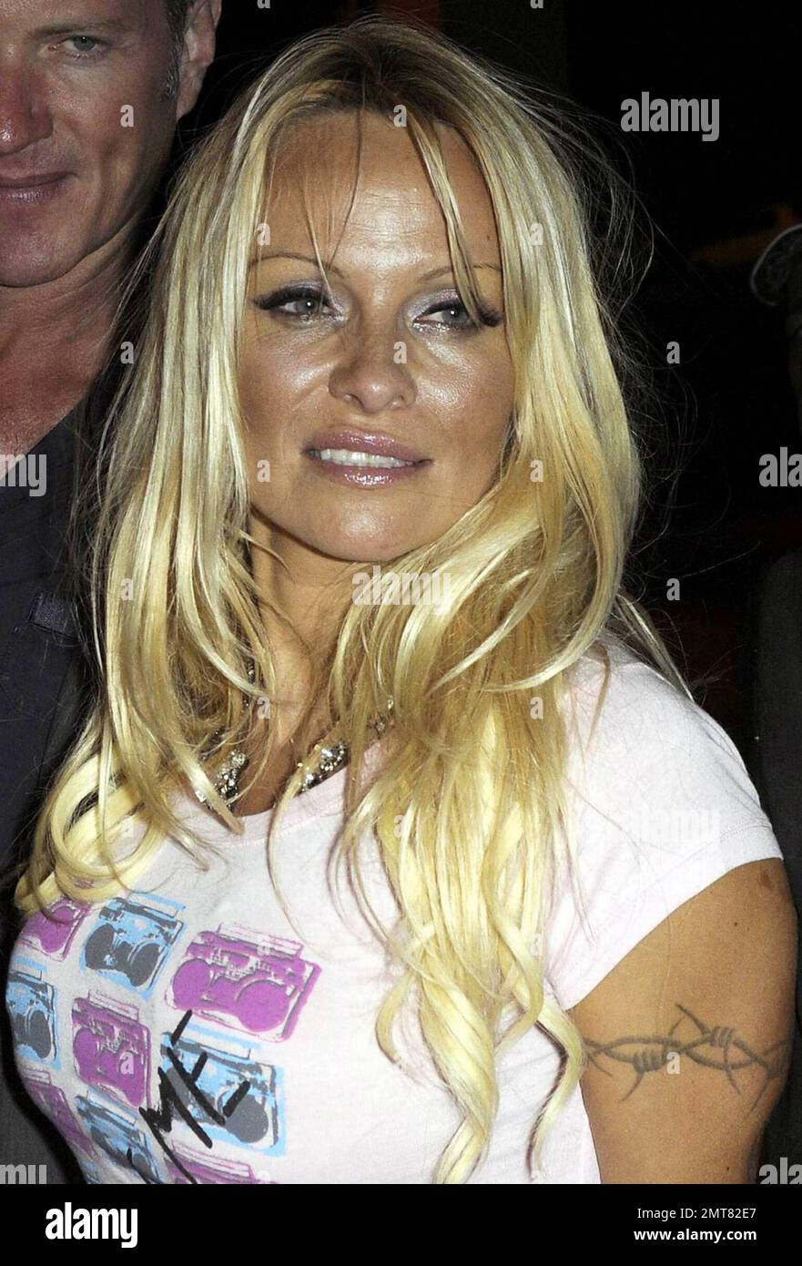 Pamela Anderson wears a baywatch bikini, accessorized with caution tape and  a scary clown mask, as she walks the runway at the fashion show for her  A*MUSE fashion line with Richie Rich
