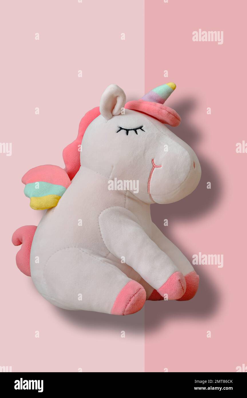 Cute soft unicorn plush toy on pink background. Close up shot Stock Photo