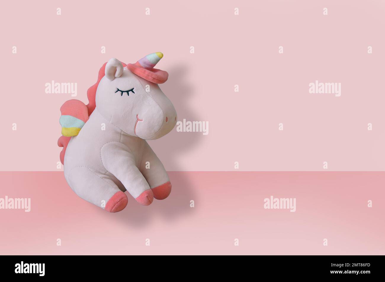Cute soft unicorn plush toy on pink background. Close up shot, empty space Stock Photo