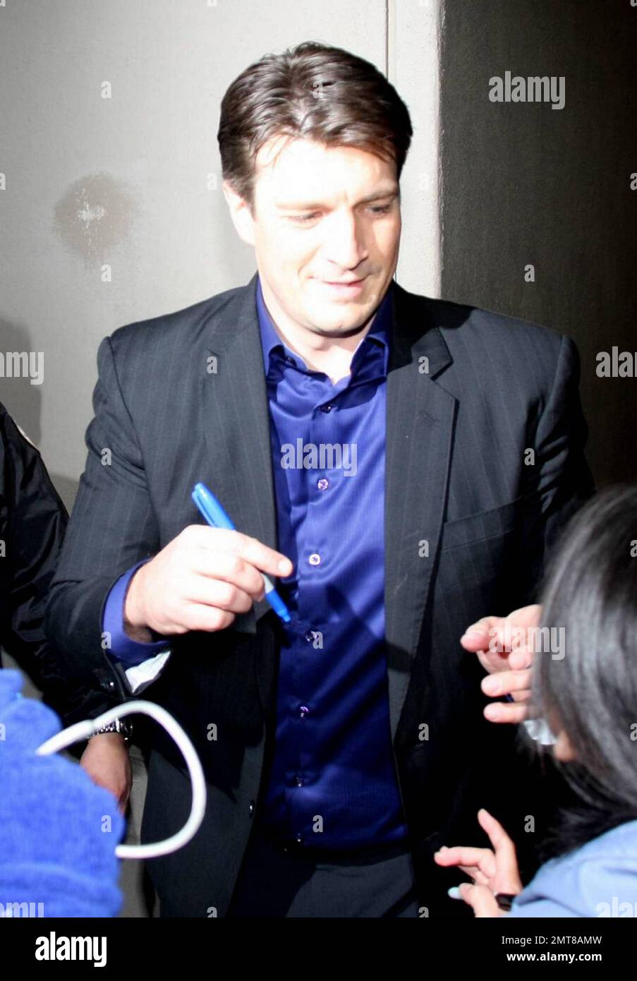 Nathan Fillion signs autographs for fans as he leaves the studios of