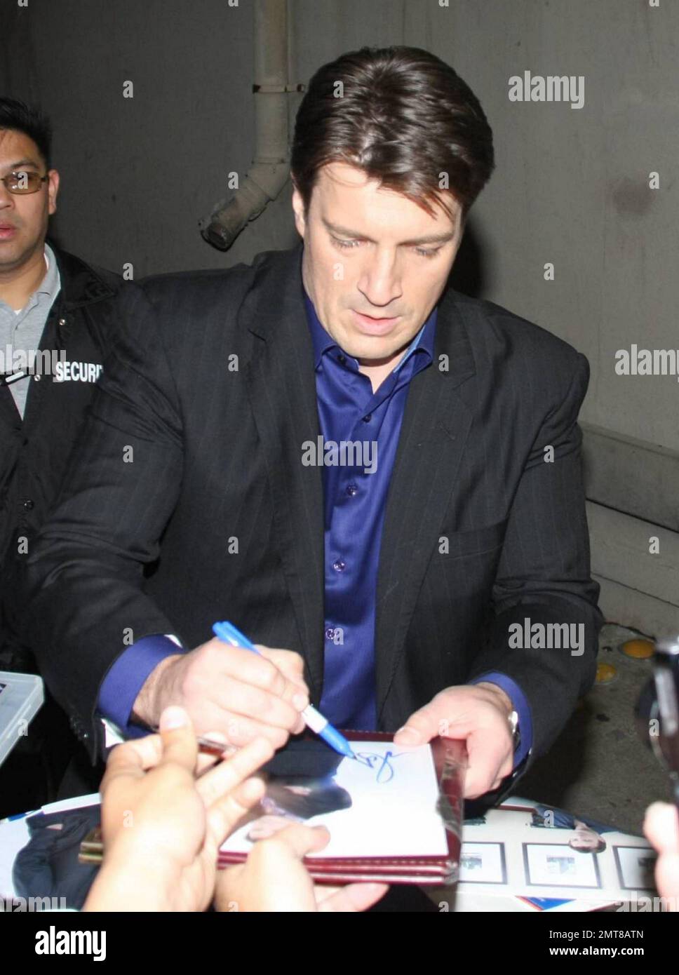 Nathan Fillion signs autographs for fans as he leaves the studios of