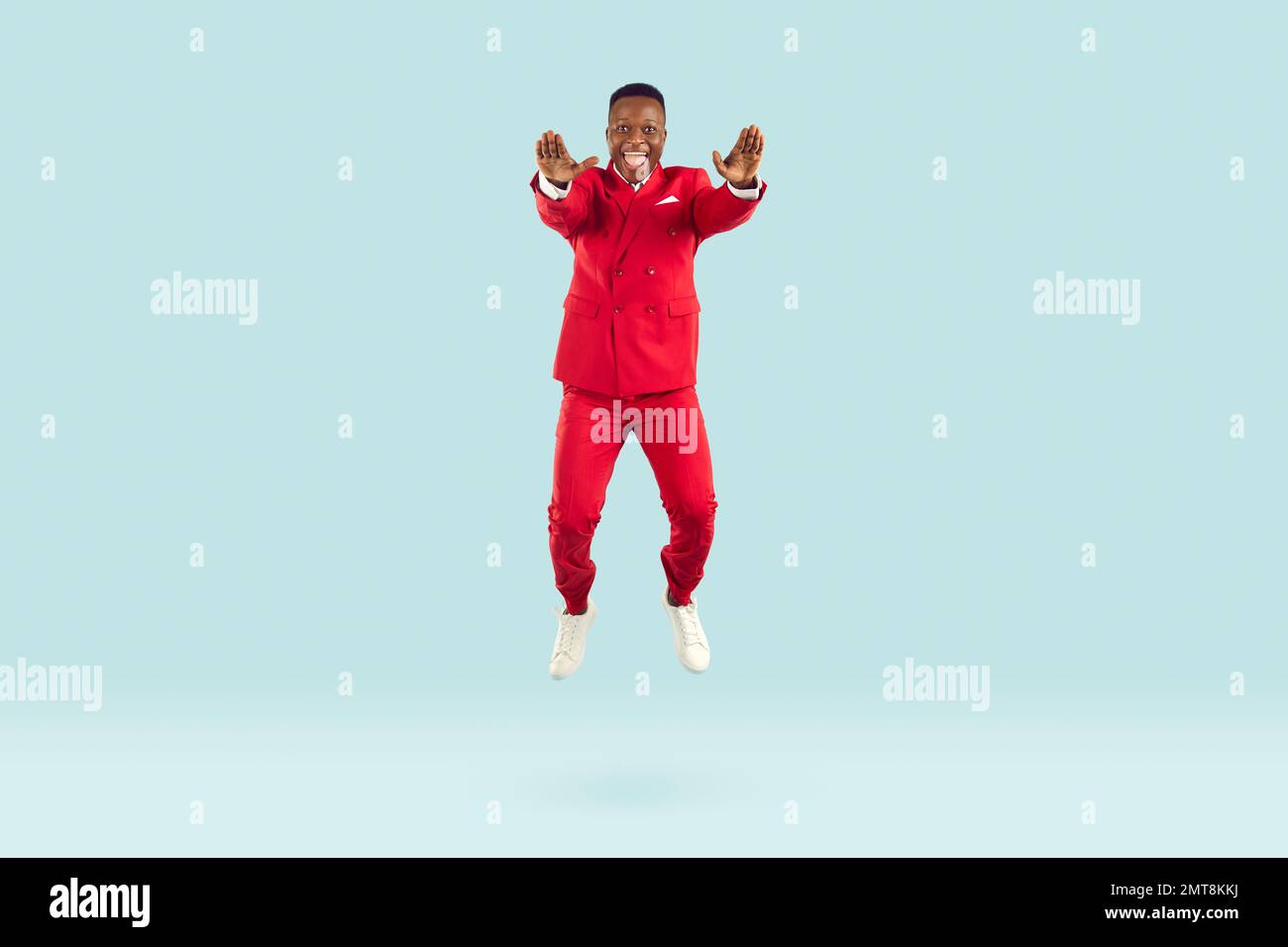 Funny stylish african american man having fun bouncing on pastel light blue background. Stock Photo