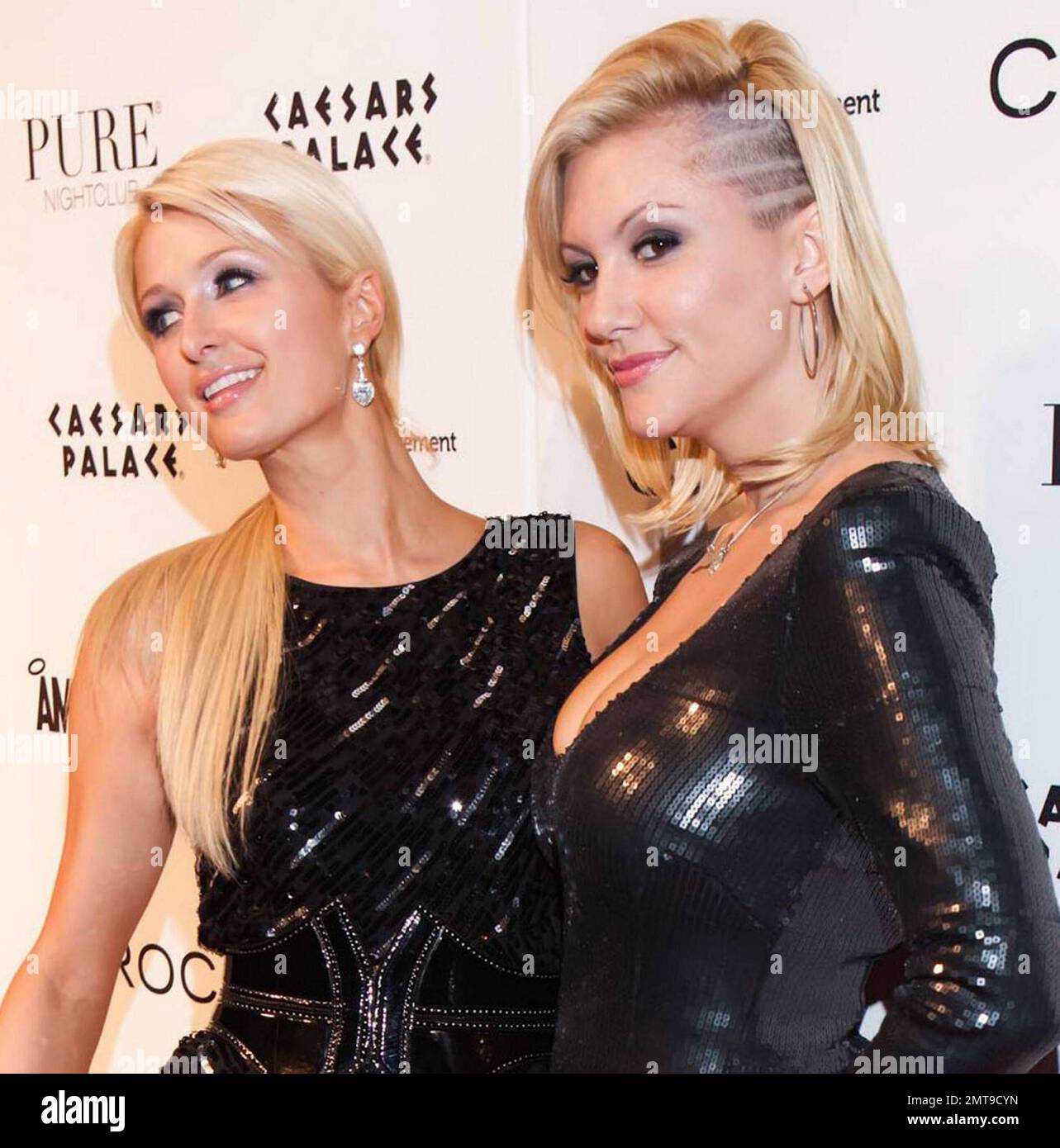 In a black sequin mini dress accessorized with a corset belt heiress Paris Hilton poses on the red carpet at Caesars Palace's Pure nightclub in celebration o Playboy playmate Jennier Rovero's 31st birthday.  On the carpet Paris, who appeared to have blemished legs and wore gold nail polish, posed with Jennier who showed o her detailed undercut hairdo. Las Vegas, NV. 12/14/10. Stock Photo