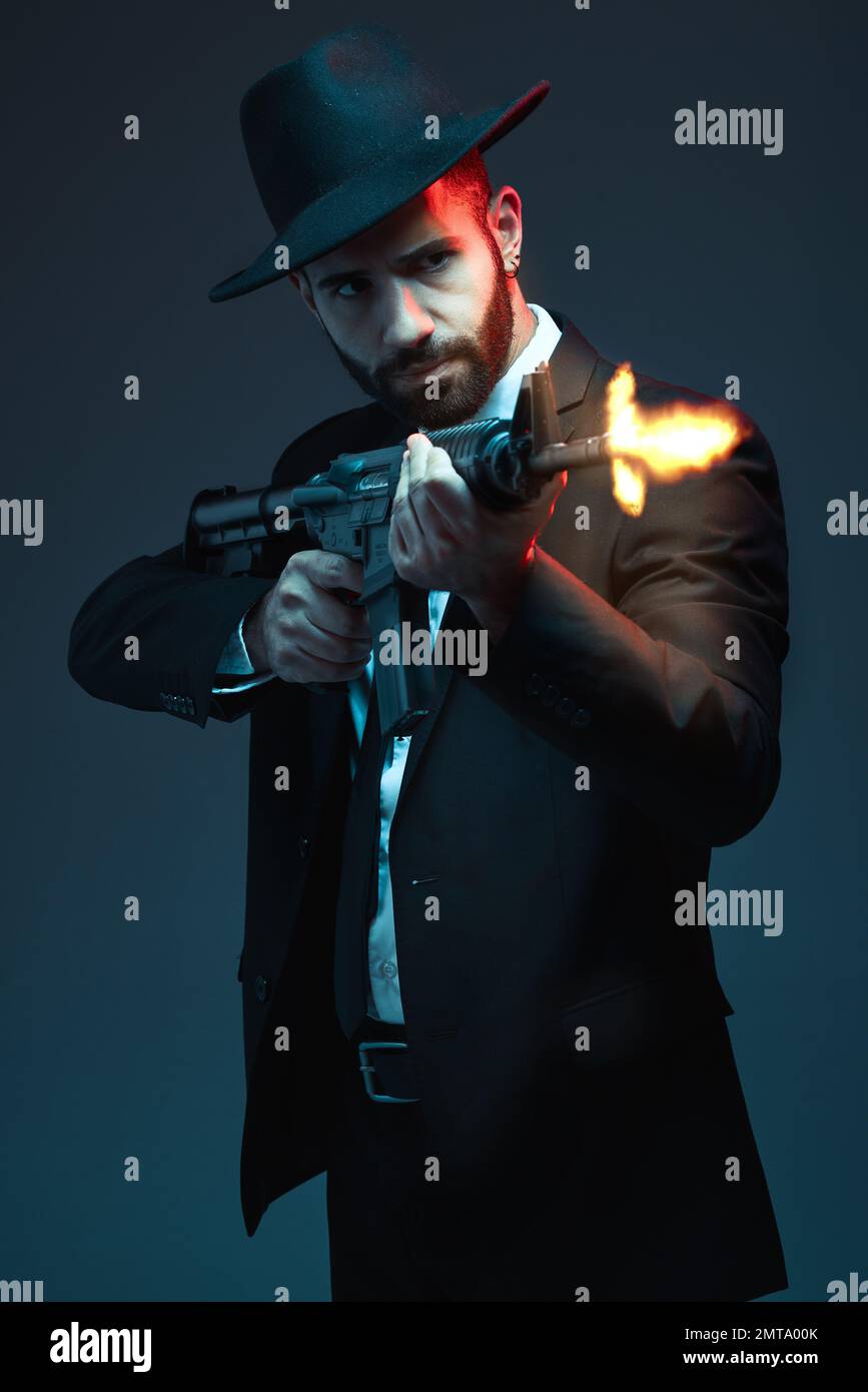 Man, suit or shooting gun on dark studio background in secret spy, isolated mafia leadership or crime lord security. Model, gangster or hitman firing Stock Photo