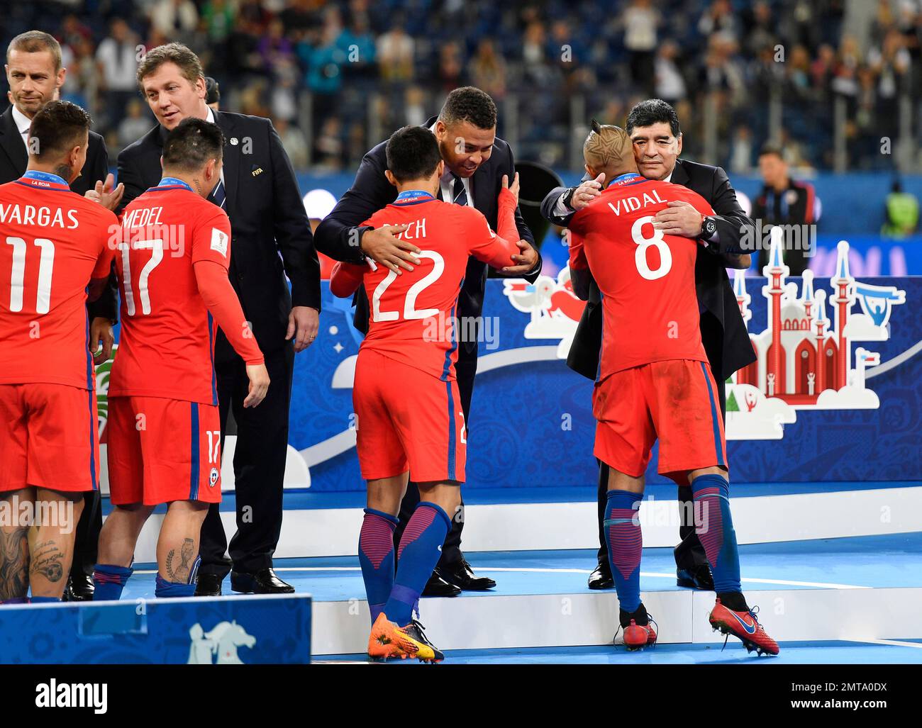 Soccer legends Diego Maradona, right, and Ronaldo comfort Chile's Arturo  Vidal, front right, and Chile's Edson Puch, center, after Germany won 1-0  in the Confederations Cup final soccer match between Chile and