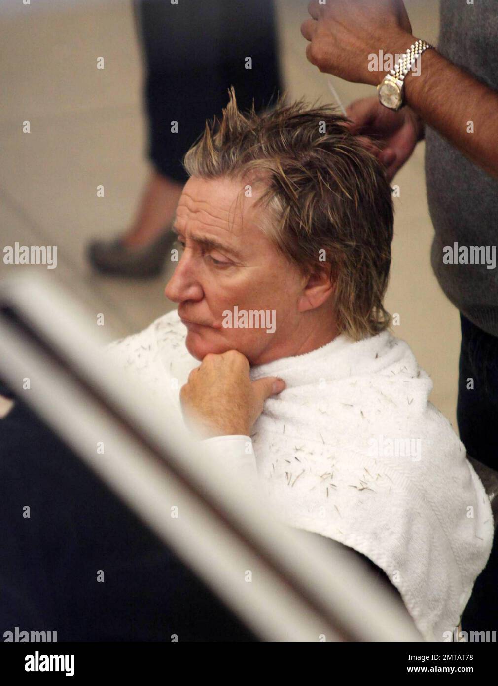 Pop rock singer Rod Stewart looks serious as he has his hair stylized