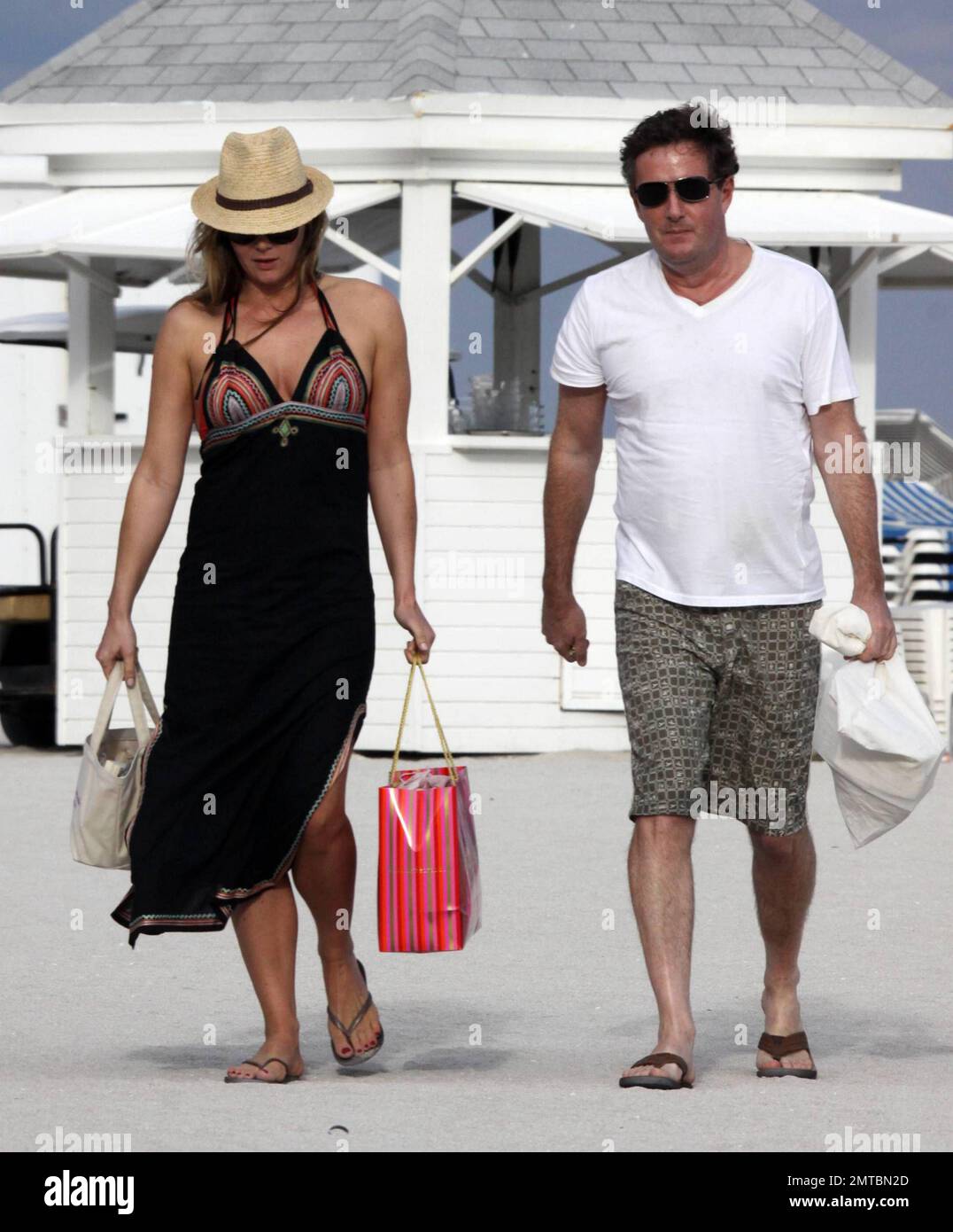 EXCLUSIVE!! "America's Got Talent" judge Piers Morgan and his writer girlfriend Celia Walden chill out together on Miami Beach.  Morgan enjoyed some down time and seemed engrossed in Michael VaughanÕs autobiography, Time to Declare whilst his stunning girlfriend sunbathed in a red bikini.  Miami, FL 1/14/2010 Stock Photo