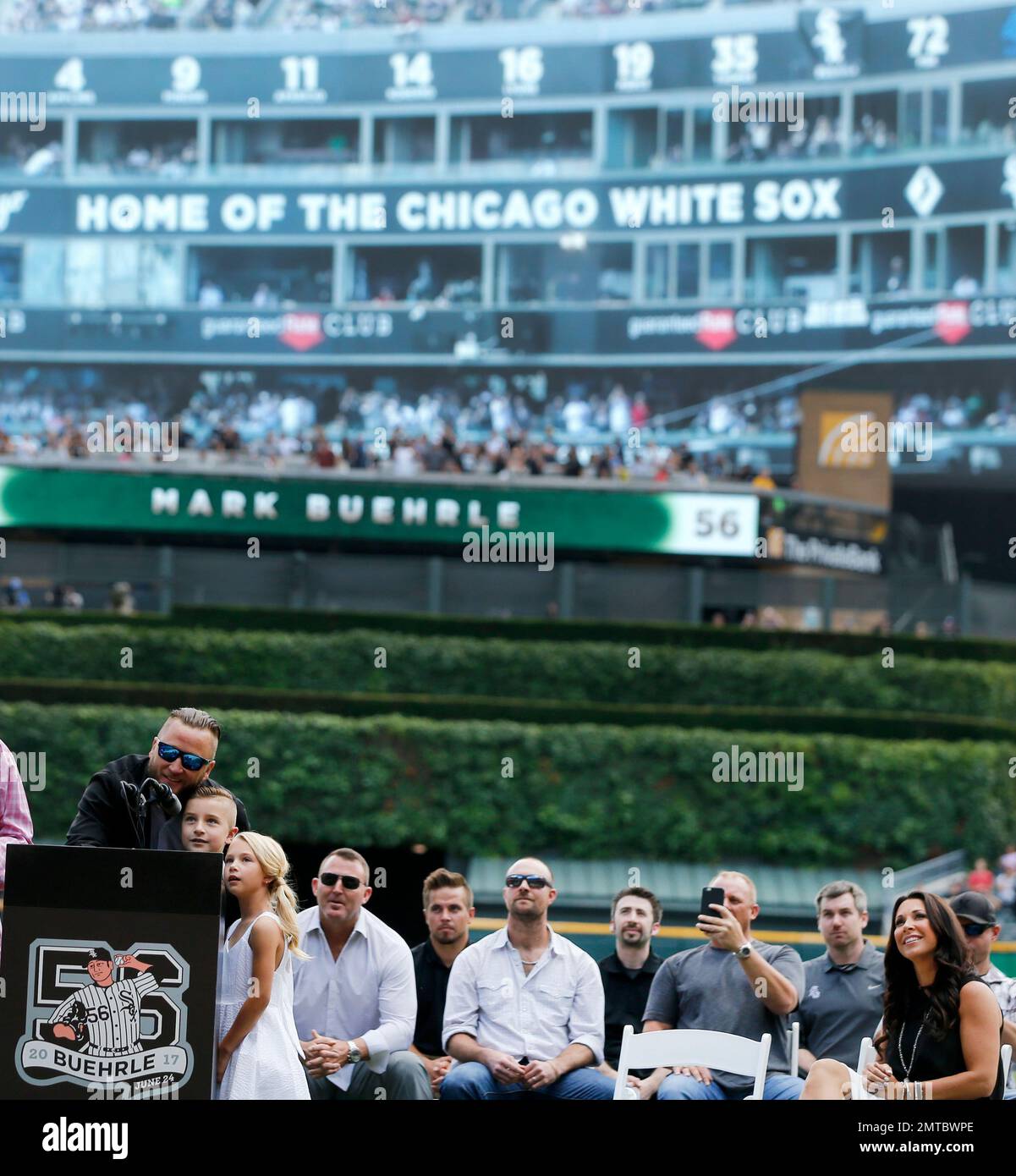 Former Chicago White Sox pitcher Mark Buehrle, left, watches with his wife  Jamie, right, daughter Brooklyn, and son Braden, as his No. 56, top right,  is retired during ceremonies before a baseball