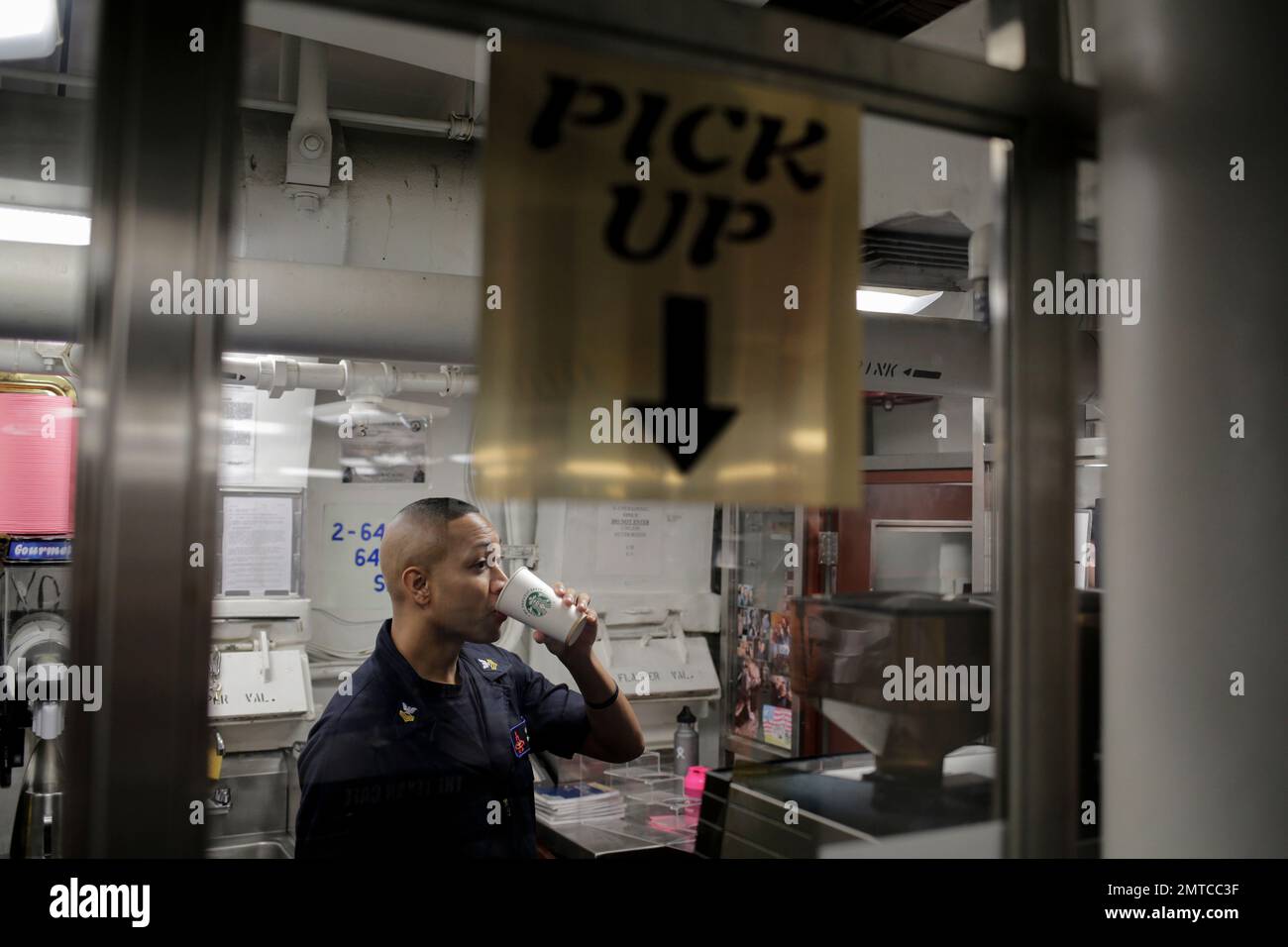 An employee drinks coffee at a Starbucks onboard the USS H.W