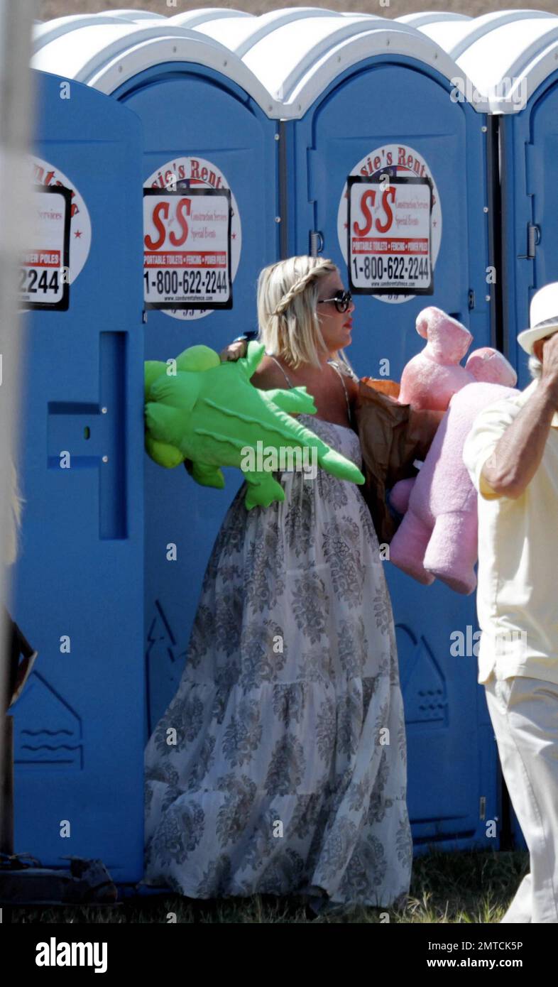 A heavily pregnant Tori Spelling in a long lose fitting white dress