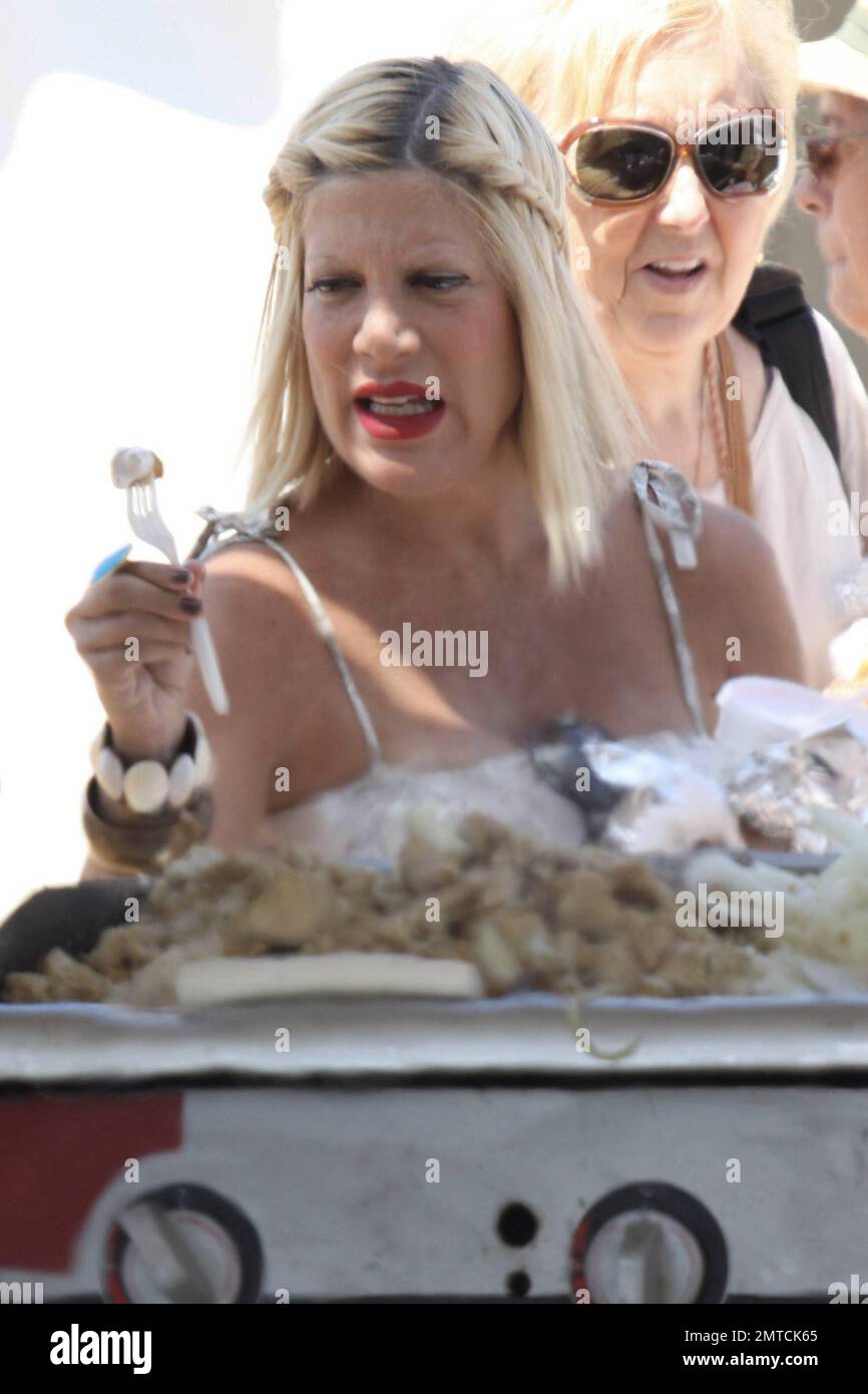 A heavily pregnant Tori Spelling in a long lose fitting white dress and