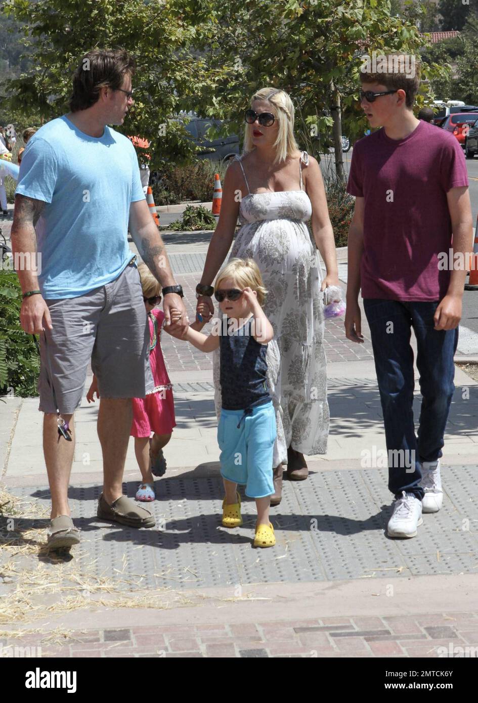 A heavily pregnant Tori Spelling in a long lose fitting white dress and