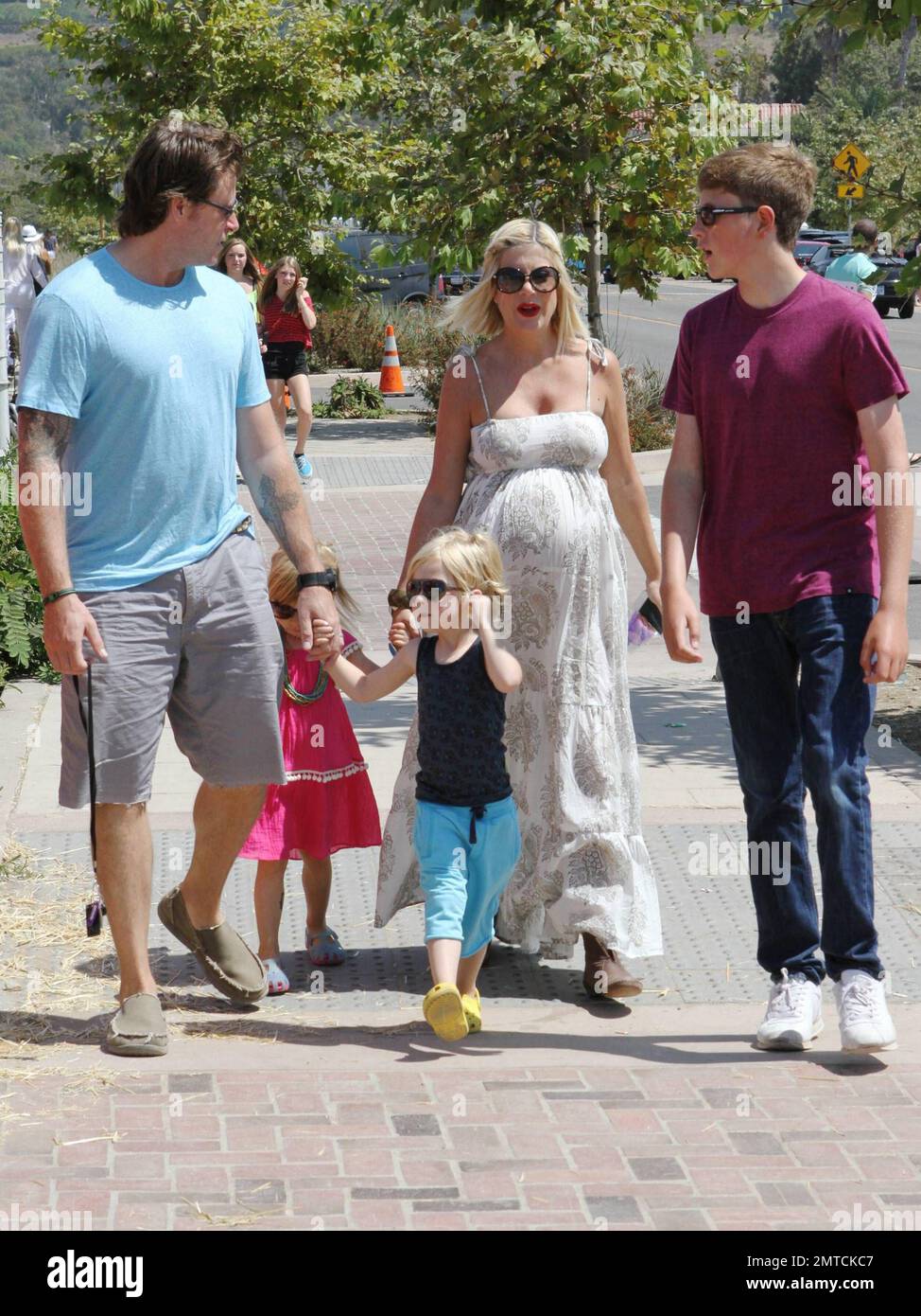 A heavily pregnant Tori Spelling in a long lose fitting white dress and