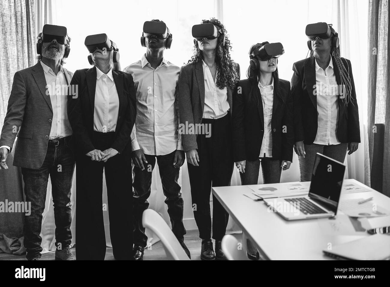 Multiracial business people wearing vr goggles inside office - Main focus on right headset - Black and white editing Stock Photo
