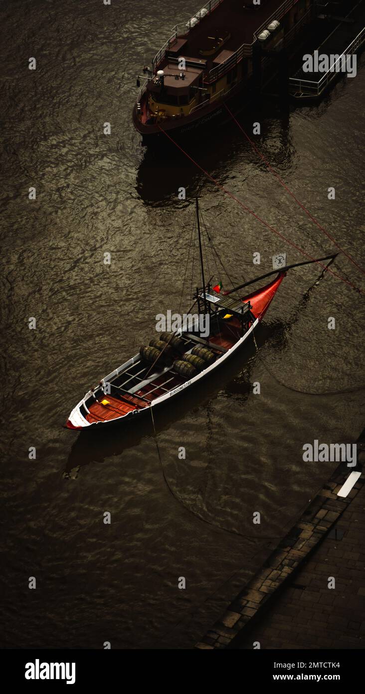 A high angle shot of a modern fishing boat in the dark black water tied to  the stone dock Stock Photo - Alamy